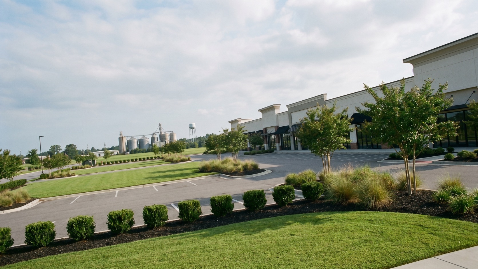 Manicured commercial property landscaping at golden hour with Katy's historic rice silos and downtown water tower beyond